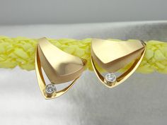 "These bold designer earrings have elegant swaths of polished yellow gold floating over a textured underlayment. A large accent diamond, weighing in at over a quarter carat, adorns the base of these abstract triangular stud earrings, giving this piece another element of sophistication. Metal: 14K Yellow Gold Gem: 2 Diamonds totaling 0.56 Carats, VS in Clarity, G in Color. Earrings Length: 30.5 mm Earring Width: 27.0 mm Marks: \"RH 14K\" Inscribed on the back of the earring SKU #: PHDW0Z-N Each p Formal Designer Diamond Earrings In Yellow Gold, Designer Yellow Gold Diamond Earrings For Formal Occasions, Formal Designer Yellow Gold Diamond Earrings, Designer Polished Finish Earrings For Anniversary, Modern Diamond Cut Diamond Earrings For Evening, Modern Diamond Accent Earrings For Anniversary, Designer Gold Diamond Earrings For Anniversary, Modern Diamond Cut Earrings For Evening, Modern Yellow Gold Diamond Earrings For Evening