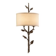 a table lamp with a white shade on it's side and leaves attached to the base