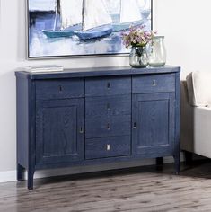 a blue sideboard with two vases on it and a painting hanging above it