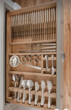 a wooden cabinet filled with silverware and utensils