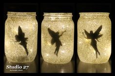 three mason jars with fairy silhouettes on them, one is lit up and the other has