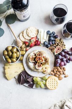 an assortment of cheeses, crackers and fruit on a plate