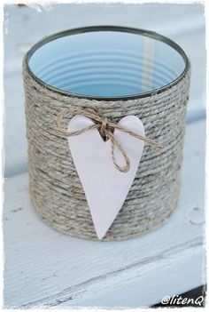 a white heart hanging from a rope wrapped candle holder