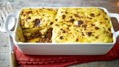 a casserole dish with meat and cheese in it on a red napkin next to a fork