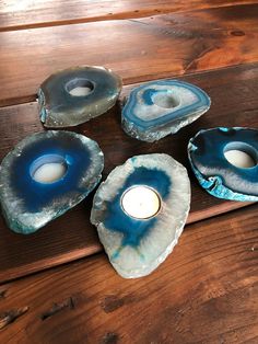 three blue agate candles are sitting on a wooden table