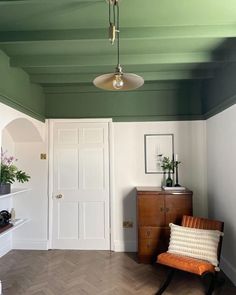 an empty room with a chair, table and lamp hanging from the ceiling in front of a door