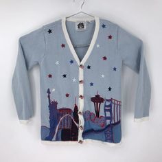 a blue cardigan sweater with an image of a city and ferris wheel on it