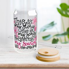 a glass jar with writing on it sitting next to a wooden coaster and a plant