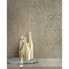 three bottles on a marble tray in front of a wallpapered background with an intricate design