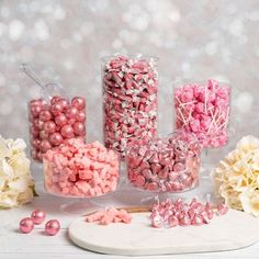 pink and white candies in glass vases on table next to hydrangeas