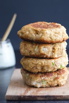 three crab cakes stacked on top of each other next to a glass of milk and a wooden cutting board