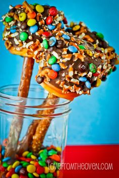 two pretzels with candy and m & ms on them in a glass jar