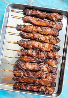 several skewered meats are on a metal tray