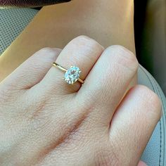 a woman's hand with a diamond ring on top of her left hand,