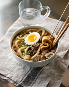 a bowl filled with noodles, meat and an egg