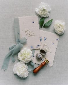 wedding rings, ring box and flowers on top of a paper with the word love written on it