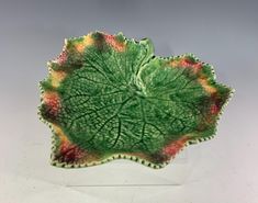 a green leaf shaped bowl sitting on top of a table