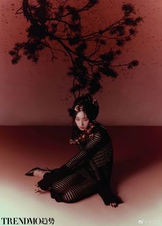 a woman sitting on the ground under a tree