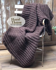 a chair with a blanket on it sitting in front of a wooden wall and a sign that says hazel throw