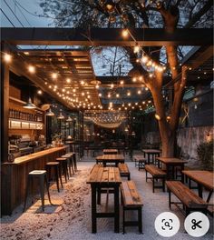 an outdoor restaurant with wooden benches and lights strung from the ceiling over it's tables