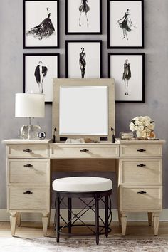 a desk with a mirror, stool and pictures on the wall