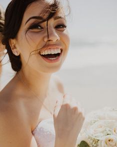 a woman is smiling and holding a bouquet