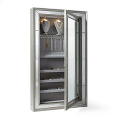 an open mirrored cabinet with silver doors and shelves filled with jewelry on the inside, in front of a white background