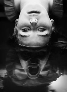 a black and white photo of a woman's face in water