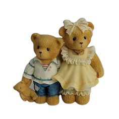 two teddy bears dressed in clothes standing next to each other