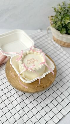 a cake sitting on top of a white plate next to a container with a pink ribbon