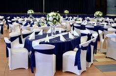 a banquet hall set up with blue and white linens, chairs, and centerpieces