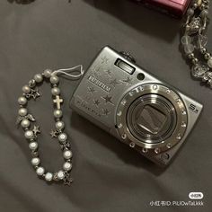 a silver camera sitting on top of a table next to a rosary and other items