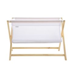 a white baby crib with a wooden frame and fabric hanging from the side, against a white background