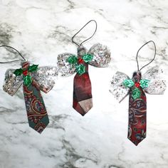 three christmas ties are hanging on a marble counter top, decorated with green and red bows