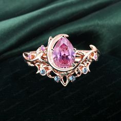 a pink ring with blue and white stones in it on a green velvet background,