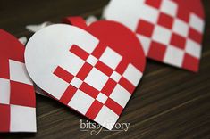 two red and white hearts cut out of paper on a table with other pieces in the background