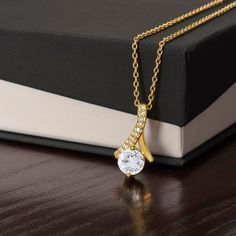 Imagine her reaction when she opens this stunning gift! The Alluring Beauty necklace features a petite ribbon shaped pendant that is sure to dazzle your special someone. Whether it's a birthday or anniversary, make sure to get her a gift she will love for years to come. 14k white gold finish or 18k yellow gold finish over stainless steel 7mm cubic zirconia Pendant dimensions: 0.8" (20mm) height / 0.4" (10mm) width Adjustable length: 18" - 22" (45.72 cm - 55.88 cm) Lobster clasp Your piece is lov Mothers Day Gift Jewelry, Wife Necklace, Valentine Gift For Wife, Ribbon Necklace, Personalized Graduation Gifts, Valentines Gifts For Her, Anniversary Gift For Her, Look At You, Gold Finish