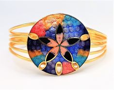 A lovely vintage cloisonne enamel bangle, c.1980s in date. In bright goldtone metal, quite a small cuff bangle formed out of four strands of wire which are open at the back. At the centre of the bangle the wire is open, and set with an enamel disc. The enamel disc has a simple flower shape in the centre and multi-coloured rainbow 'tie-dye' effect enamels all over. Really good fun! Approx. 32mm wide, the bangle is 55mm by 45mm and the opening is 33mm. Quite small for an adult, but it fits my wris Adjustable Enamel Bangle As A Gift, Adjustable Enamel Bangle As Gift, Adjustable Enamel Cuff Bracelet As Gift, Adjustable Enamel Cuff Bracelet For Gift, Adjustable Enamel Bangle For Gift, Handmade Enamel Bangle, Multicolor Hand Painted Bangle Jewelry, Hand Painted Multicolor Bangle Jewelry, Adjustable Enamel Bangle