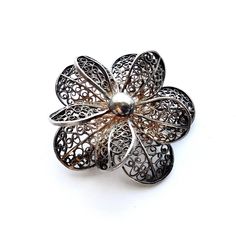 "Available to you is this great vintage filigree flower brooch. Although it has what looks like a little plate on the back it is unmarked. It is ten-petaled and just lovely. Side views and a video are included so you can appreciate all of the 3-D details of this great find. It has a primitive \"C\" catch, and the pin sticks out a little from the back edge, which generally indicates an older piece. This floral pin measures 1.75\" in diameter and 0.5\" thick. It weighs in at 12.8 grams. There is a Vintage Filigree Flower Brooches, Ornate Flower Brooch As A Gift, Vintage Silver Flower Brooches, Ornate Flower Brooches As Gift, Ornate Flower Brooch With Filigree, Floral Pins, Gold Cocktail Ring, Bangor, Botanical Beauty