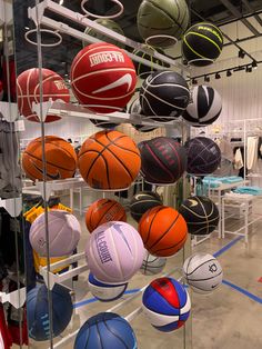 several basketballs are on display in a store with other sports balls hanging from the ceiling