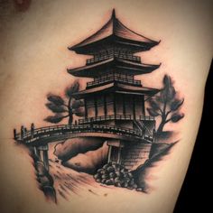 a black and white photo of a japanese pagoda tattoo on the back of a woman's shoulder