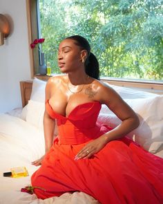 a woman in a red dress sitting on a bed