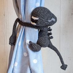 a crocheted stuffed animal hanging from the side of a curtain with polka dots on it