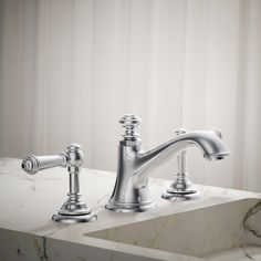 a bathroom sink with two faucets and marble counter top