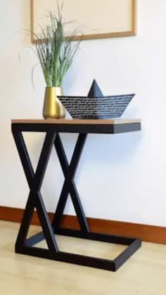 a small table with a vase on it and a paper boat sitting on top of it