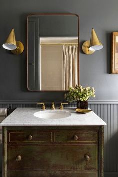 a bathroom sink sitting under a mirror next to a wooden cabinet with two lights on it