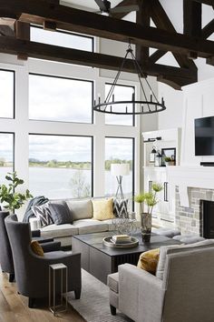 a living room with couches, chairs and a television mounted to the wall in front of large windows