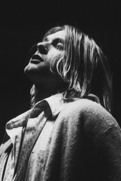 a black and white photo of a man with long hair looking off into the distance