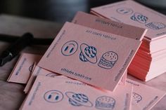 stacks of pink business cards sitting on top of a table next to a pair of scissors