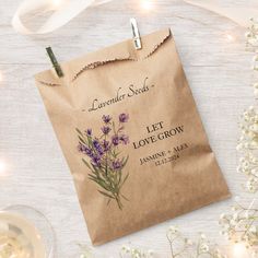 a brown paper bag with lavender seeds on it next to some wine glasses and flowers